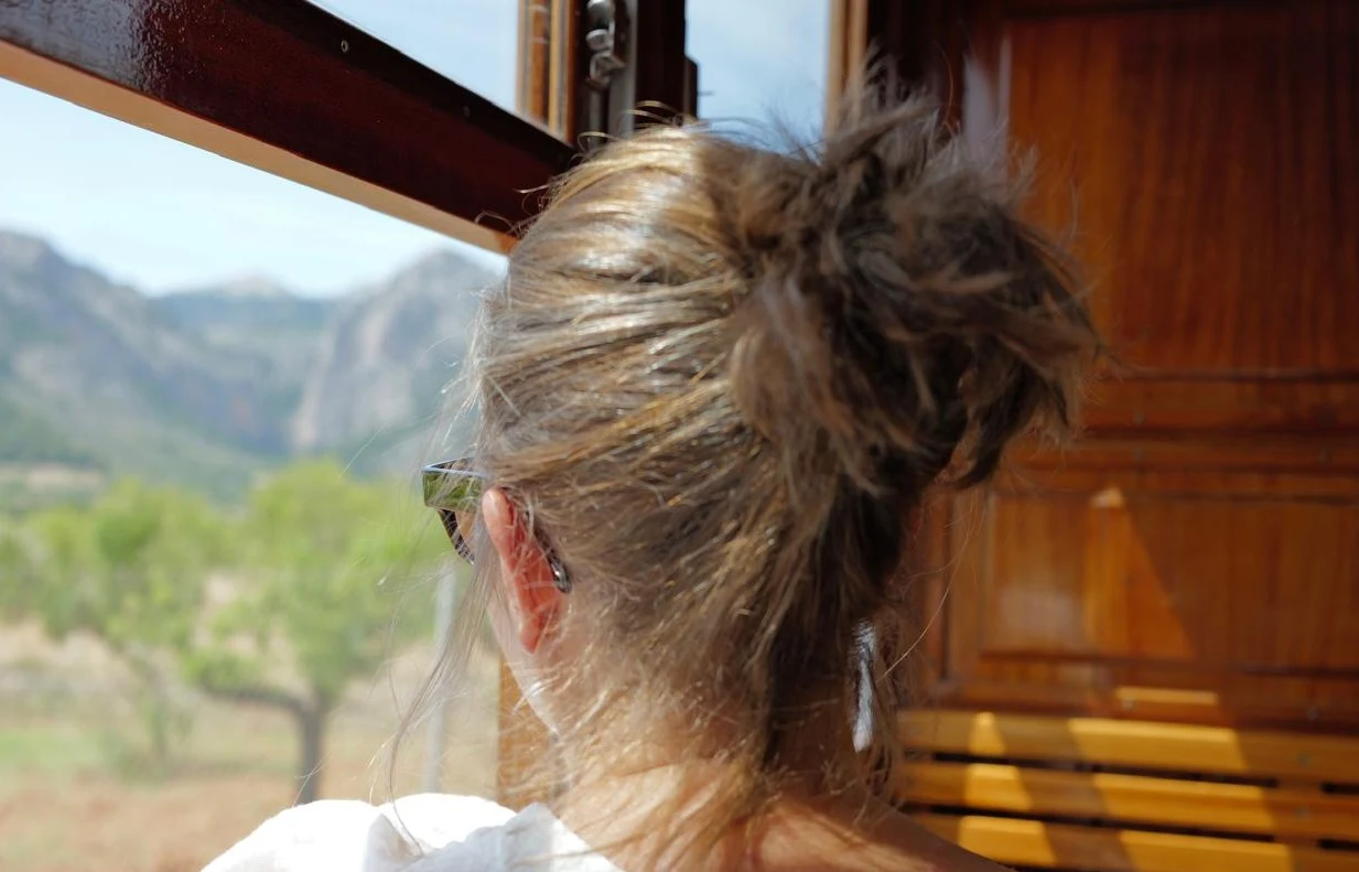Maria Bauriedl looking through a train window toward sunlit mountains